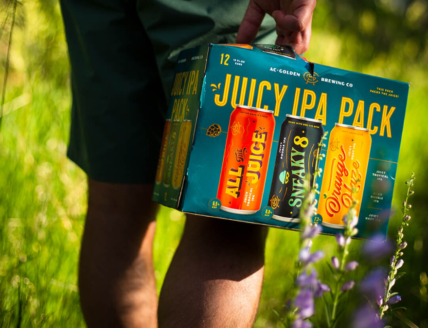 person walking in nature with twelve Juicy Ipa Pack in hand